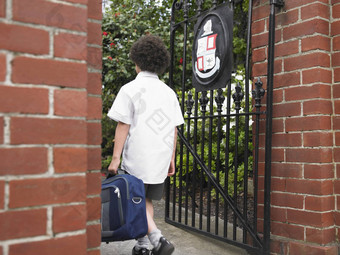 后视图年轻的男孩背包进入学校门