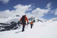 后视图徒步旅行者加入安全行雪山
