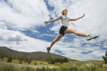 低角视图年轻的女人跳跃农村景观