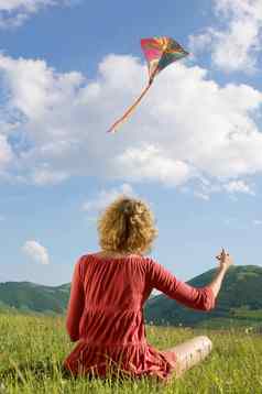 后视图年轻的女人飞行风筝公园