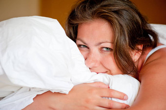 年轻的女人拥抱枕头床上