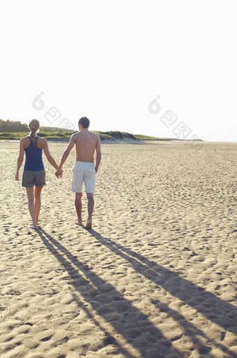 完整的长度后视图夫妇走手手海滩
