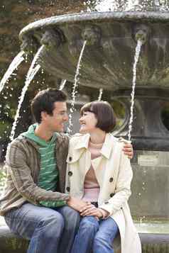 拥抱年轻的夫妇坐着边缘喷泉