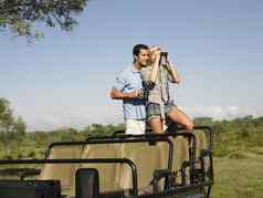 年轻的夫妇Safari站吉普车双筒望远镜