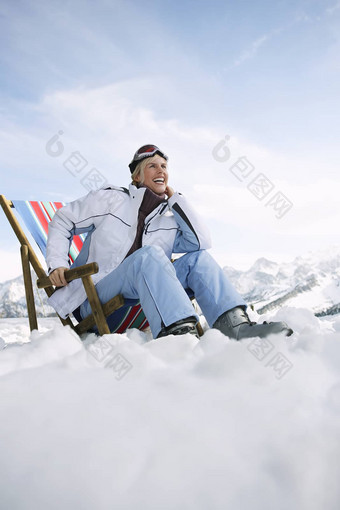 低角视图微笑女人坐着帆布躺椅雪山