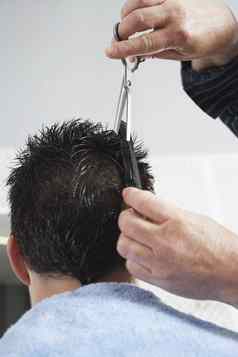 特写镜头理发师切割男人的头发理发师商店