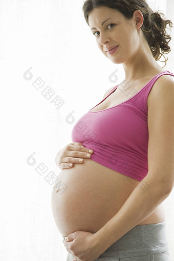 肖像美丽的年轻的怀孕了女人站白色背景