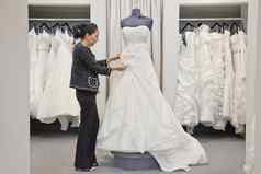 一边视图成熟的员工调整优雅的婚礼衣服新娘商店