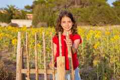 微笑农民女孩向日葵场持有栅栏通过