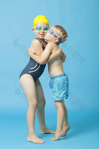年轻的兄弟姐妹泳装拥抱接吻蓝色的背景