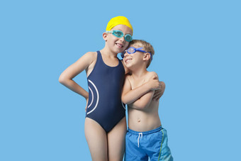 快乐年轻的兄弟姐妹泳装手臂蓝色的背景