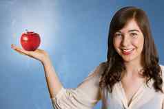 美丽的年轻的女人持有红色的苹果