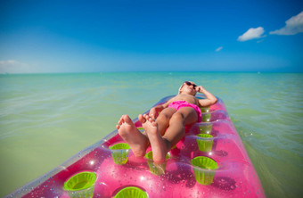 可爱的女孩粉红色的气床日光浴加勒比海