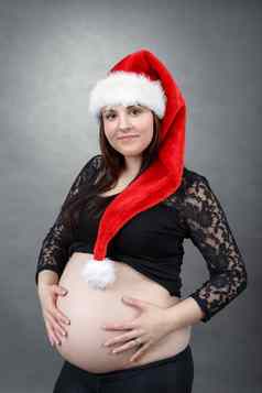 美丽的怀孕了圣诞老人女人温柔持有肚子