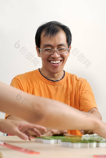 快乐微笑亚洲男人。玩麻将