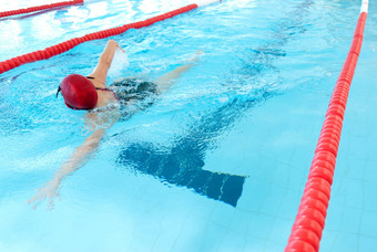 年轻的女人游泳室内池自由泳模式