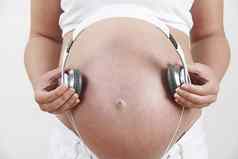 关闭怀孕了女人持有耳机肚子