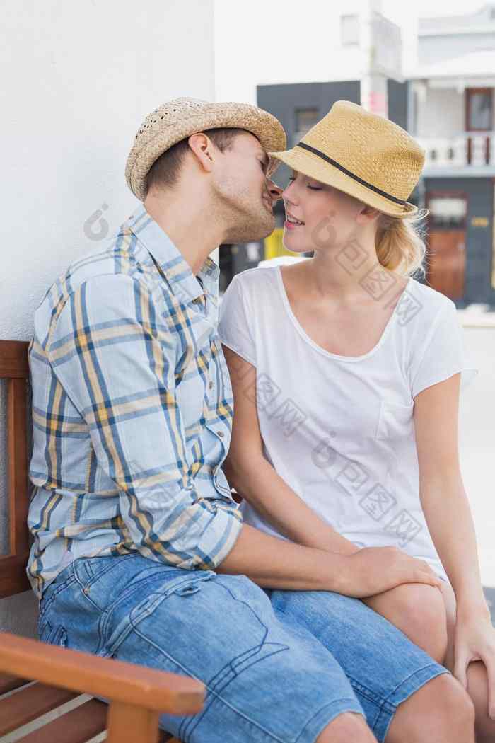 年轻的臀部夫妇坐着板凳上吻