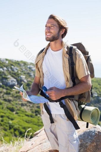 英俊的徒步旅行者持有地图指南针山峰会