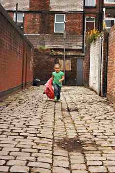 年轻的黑色的婴儿女孩玩鹅卵石用石头砸小巷