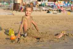 满意一年女孩坐着海滩涂上湿沙子