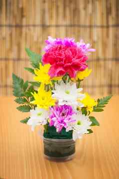 色彩斑斓的花花束安排花瓶木背景