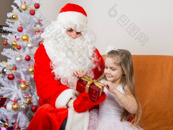 女孩释放了红色的丝带礼物圣诞老人老人手