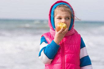 五年女孩吃苹果背景海海岸