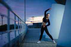有吸引力的健身女孩锻炼现代城市区域日落