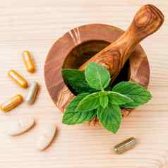 新鲜的薄荷叶子橄榄木砂浆胶囊Herbal医学替代健康护理概念设置木背景