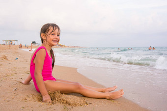 五年女孩坐在海滩海边有趣的距离