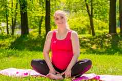 美丽的年轻的怀孕了女人公园席瑜伽