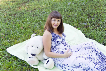 怀孕了女人大白色玩具熊绿色草