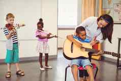 老师协助孩子们玩音乐的仪器教室