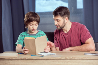 肖像父亲帮助集中儿子阅读书