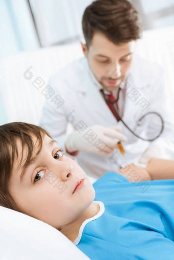 生病的男孩说谎医院床上男人。医生使注射
