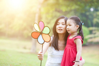 妈妈。女儿<strong>玩风车</strong>绿色公园