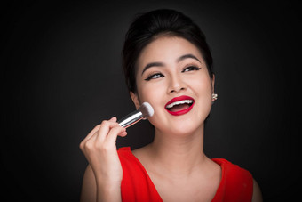 化妆品粉刷亚洲女人应用脸红的人脸颊