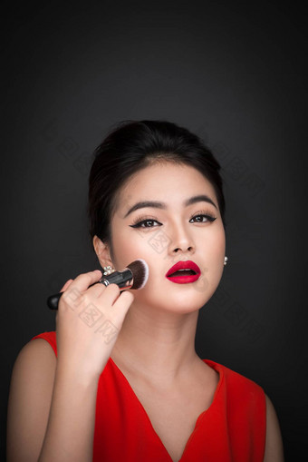 化妆品粉刷亚洲女人应用脸红的人脸颊
