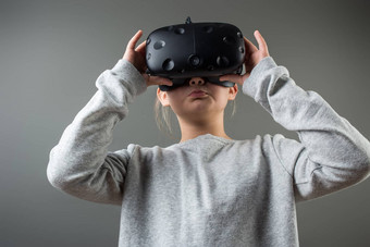 女孩穿虚拟现实护目镜站灰色背景眼镜度虚拟现实耳机游戏穿虚拟现实护目镜智能手机虚拟现实视频