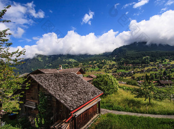 美丽的全景明信片视图风景如画的农村山风景阿尔卑斯山脉传统的高山山小木屋新鲜的绿色梅多斯阳光明媚的一天蓝色的天空云夏天
