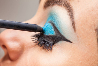 化妆艺术家应用蓝色的眼影白色女人眼睛