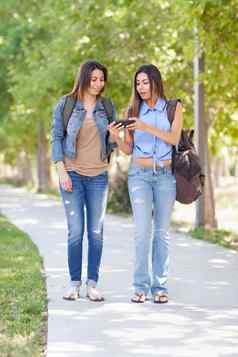 美丽的年轻的少数民族双胞胎姐妹背包智能手机