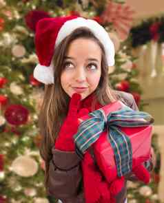 思考女孩穿圣诞节圣诞老人他弓包装礼物前面装饰树