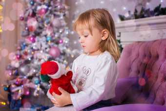 女孩坐在沙发持有玩具圣诞老人老人手