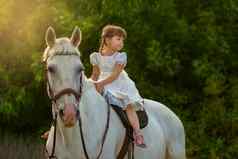 女孩坐在马两腿分开着