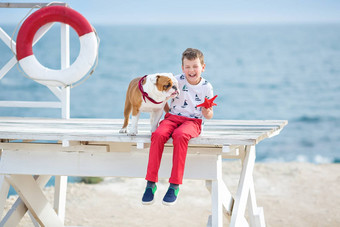 英俊的男孩青少年快乐支出时间朋友斗牛犬海一边孩子狗持有玩海星星关闭生活浮标浮动穿红色的<strong>裤子裤子</strong>拖鞋t恤