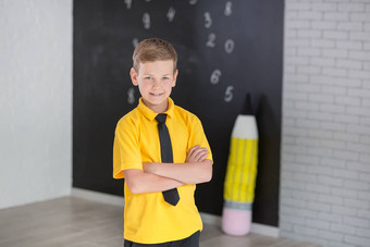 可爱的英俊的学校男孩黄色的t恤领带时尚的靴子casuals站陈词滥调黑色的董事会数字持有巨大的大软玩具铅笔微笑
