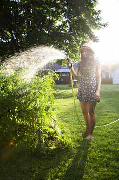 年轻的女人浇水花园
