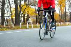 年轻的女人橙色夹克骑路自行车公园冷秋天一天健康的生活方式